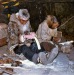 1950s Carving ivory. Kotzebue, AK. Wearing beaver skin parka with wolf ruff. Ruffon right is wolverine skin.