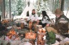Oliver, Heidi and one other sitting around campfire. Teepee in background. Norway