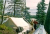 Joyce and Dan Denslow in front of white wall tent.  Ambler River in the background, small wood stove beside the tent.